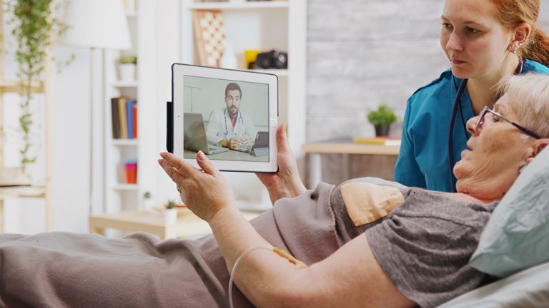Nurse and patient virtually speaking to doctor on tablet